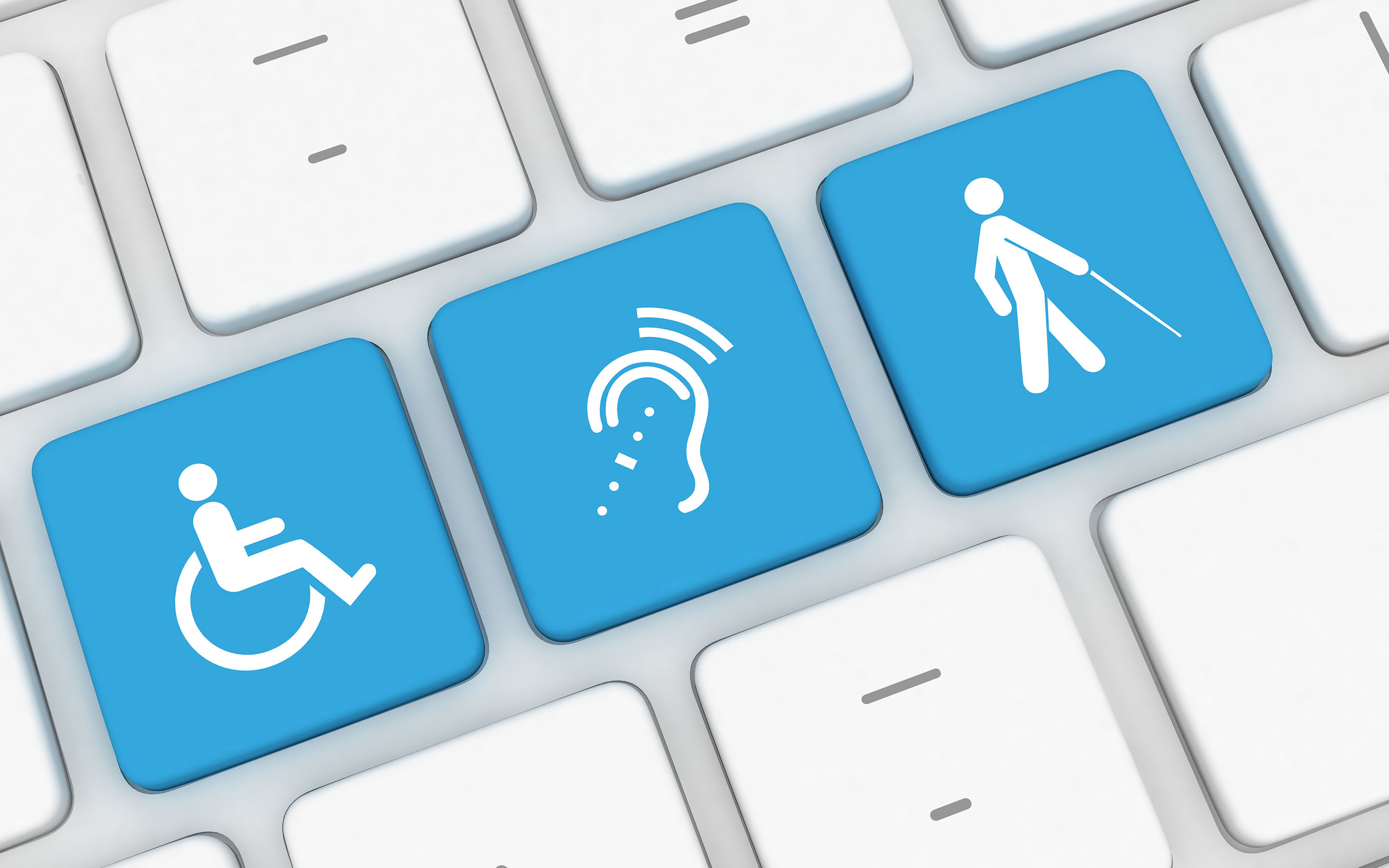 A computer keyboard with three keys showing disability access symbols. The three keys have a blue background and square white symbols that stand out from the other letters on the keyboard. The first key shows the International Symbol of Access (ISA), the international symbol for wheelchair accessibility. The second denotes assistive listening systems. The third is the visual impairment symbol.